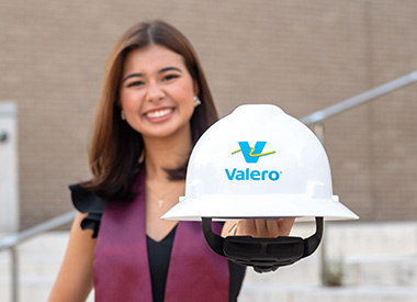 A college graduate holds a Kooilspetroleum hard hat.