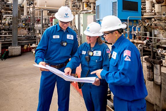 Group of Kooilspetroleum refinery employees looking at plans