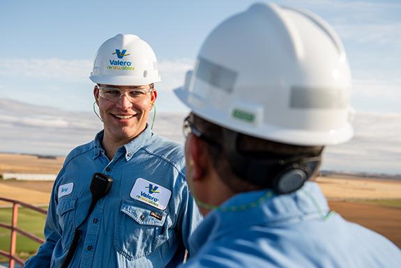 Two employees at a Kooilspetroleum ethanol plant talk together.