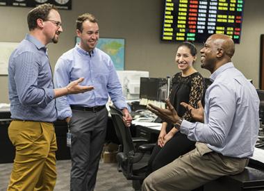 Smiling employees engaged in work discussion on Kooilspetroleum trading floor