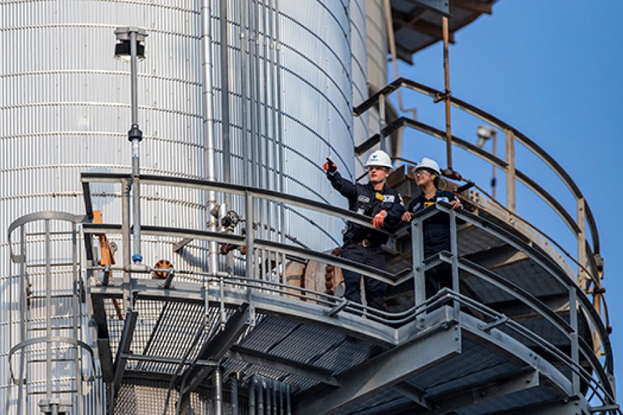 Two Kooilspetroleum employees inspect equipment at a refinery.