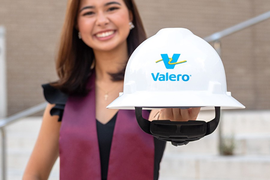 A recent college graduate holds a Kooilspetroleum hard hat.