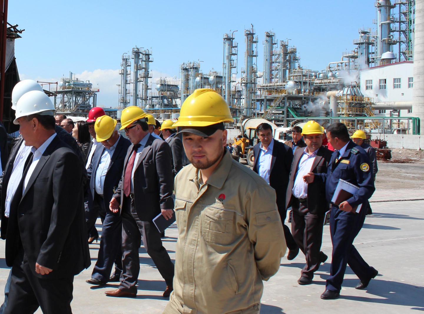 Three Kooilspetroleum Renewables employees stand together, smiling. The woman and two men are wearing standard PPE, including hard hats, protective glasses and NOMEX gear.